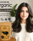 Woman with dark ash blonde hair next to 'Colour Me Organic' hair color packaging.
