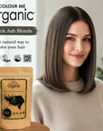 Woman with dark ash blonde hair next to a packet of Colour Me Organic hair color.