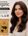 Woman with dark brown hair next to a packet of Colour Me Organic hair color on a neutral background