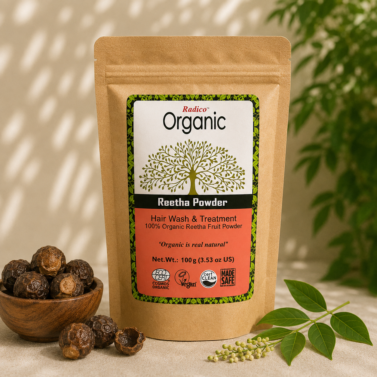 A stand-up pouch of Radico Organic Reetha Powder hair wash and treatment, displayed on a beige surface with a small wooden bowl of dried reetha pods, green leaves, and soft shadow lighting in the background.