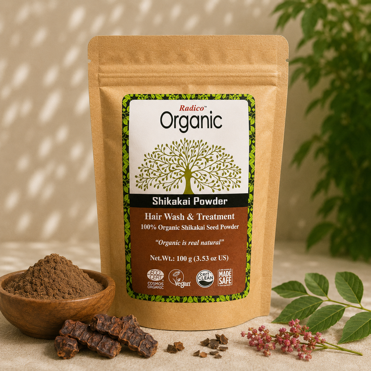 A stand-up pouch of Radico Organic Shikakai Powder hair wash and treatment, shown with a bowl of loose powder, dried shikakai pods, and green leaves on a neutral surface.